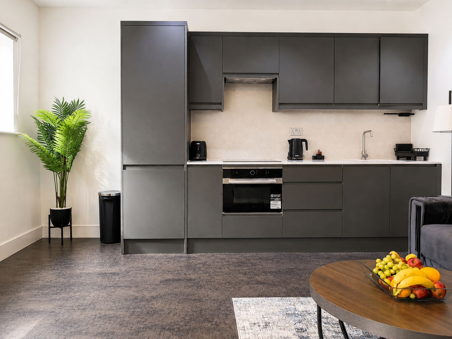 Eine moderne Küche mit grauen Schränken, einem eingebauten Backofen und einer Kaffeemaschine.