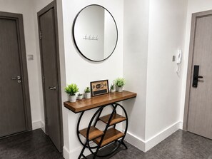 A hallway with a wooden console table, a round mirror, and a small potted plant. - Modern 2 Bedroom Serviced Apartment West Street Sheffield (Sheffield)
