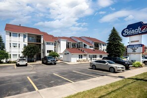 A hotel with multiple buildings, a parking lot, and a sign advertising daily weekly availability on Airbnb and VRBO. - Tidal Retreat 217 | Balcony | Direct Beach Access | Near Downtown & TART Trail (Traverse City)