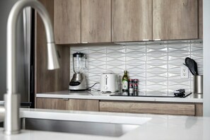 Cozinha moderna com liquidificador embutido, torradeira e painel de azulejos branco.