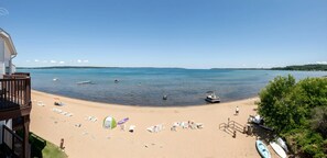 A beach with clear skies, a sandy shore, and a view of the sea. - Tidal Retreat 217 | Balcony | Direct Beach Access | Near Downtown & TART Trail (Traverse City)