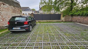 Ein schwarzes Auto steht in einem Innenhof mit einer Backsteinmauer und einem Gitterrostboden.