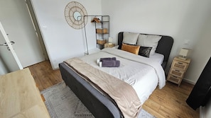 Ein modernes Schlafzimmer mit Bett, Nachttischen, einer Stehlampe und einem Kleiderschrank.