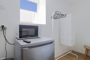 A compact kitchenette with a microwave, a small refrigerator, and a window with a view of a building. - Le Nid Cosy 4, Balnéo 2 lits wifi (Tourcoing)