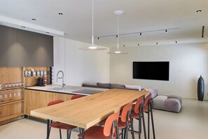 A modern kitchen with a wooden dining table, red chairs, and a built-in coffee machine. - MiCasa Jacuzzi & Rooftop SicilyMyHome (Noto)