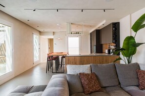 A modern living room with a grey sofa, a coffee table, and a large plant. - MiCasa Jacuzzi & Rooftop SicilyMyHome (Noto)