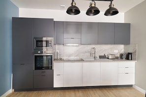 A modern kitchen with a built-in oven, microwave, and stainless steel sink. - Prestige stay with les Halles view, A/C (Béziers)