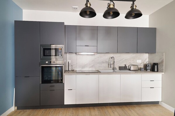 Cozinha moderna com forno embutido, micro-ondas e pia de aço inoxidável.