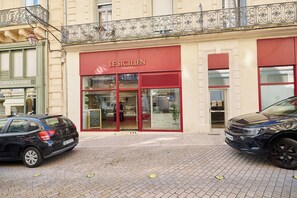 Um edifício com fachada onde se lê 'LE SICILIEN TRAITEUR' e um anúncio para 'DECORATIONS INTERIEURES'.
