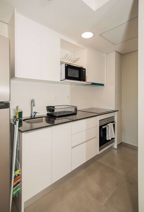 A modern kitchen with white cabinetry, a black countertop, a microwave, and a stainless steel oven. - Modern Two-Bedroom in Luque with Pool&Gym Access (Luque)
