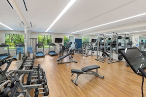 A gym with various exercise equipment, large windows, and a wooden floor. - Oceanfront Condo at One Cable Beach (Nassau)