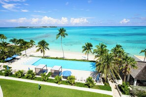 A resort with a pool, palm trees, and a beach view. - Oceanfront Condo at One Cable Beach (Nassau)