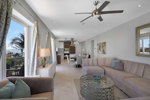 A modern living room with a sofa, a coffee table, and a ceiling fan. - Oceanfront Condo at One Cable Beach (Nassau)