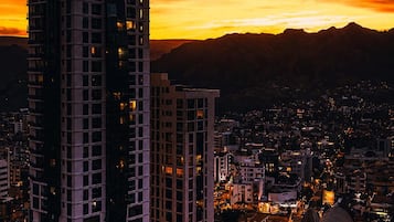 Ein Stadtbild im Abendlicht mit Hochhäusern und einem Bergpanorama im Hintergrund.