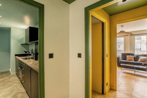 A modern kitchen with built-in appliances, a dining area with a sofa, and a view of the city. - The Collection - Stylish 3BD next to Invalides! (Paris)