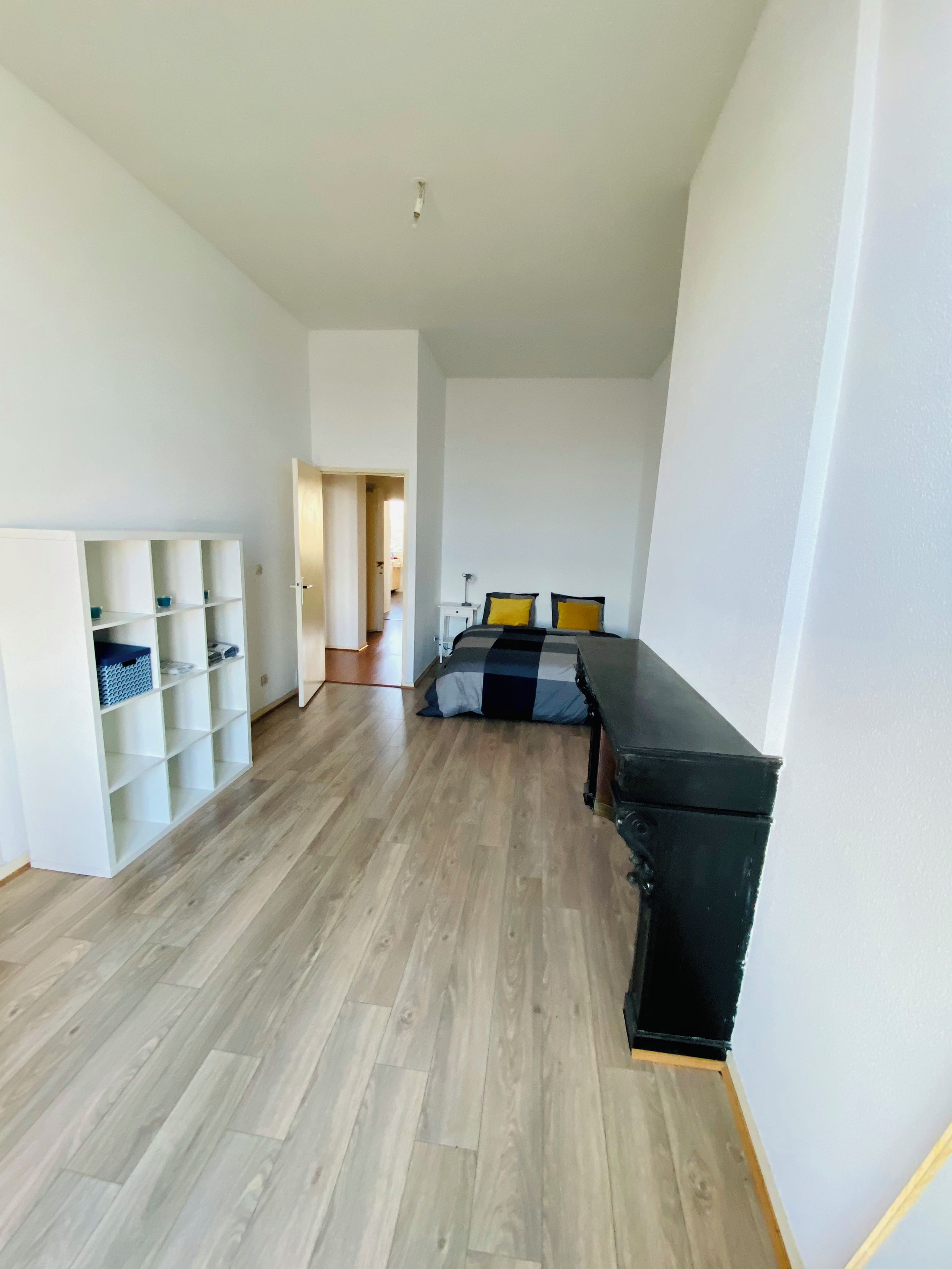 A room with a bed, a desk, and a shelving unit.