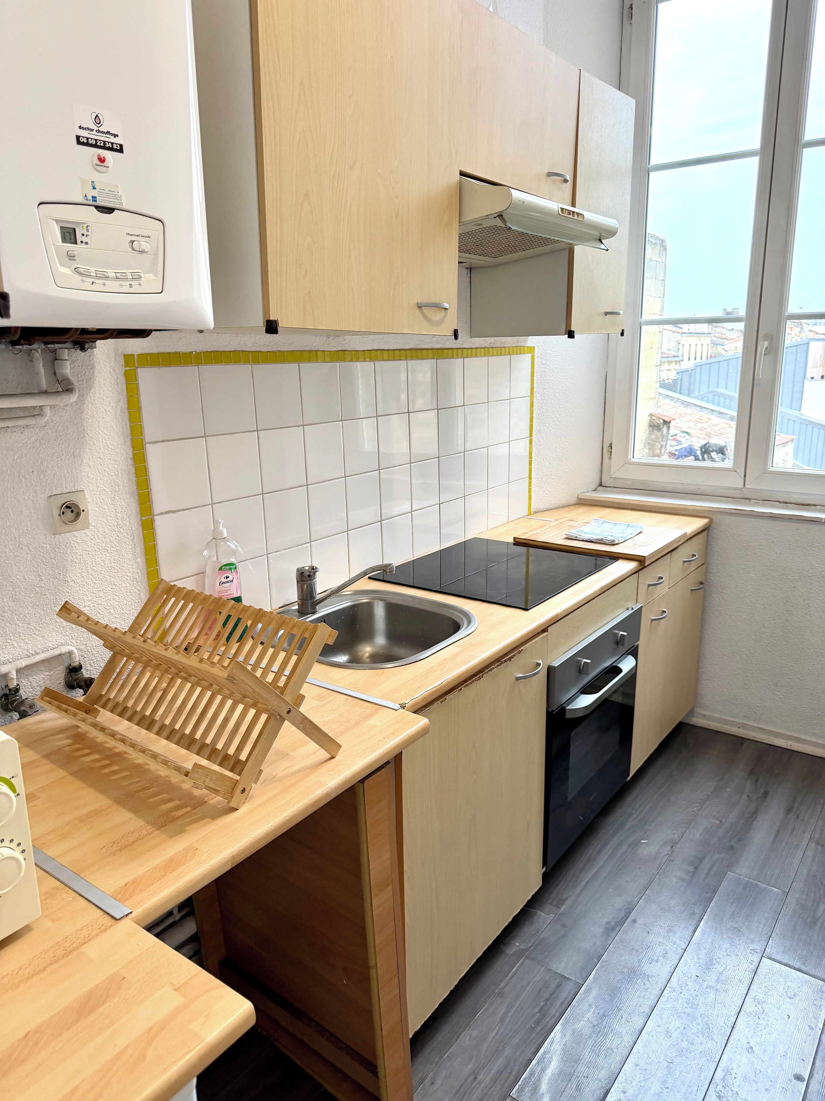 A compact kitchen with a sink, stove, and wooden countertop.