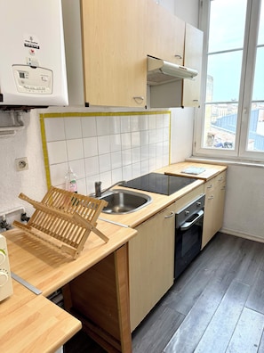 Een kleine keuken met een spoelbak, fornuis en een houten aanrecht.