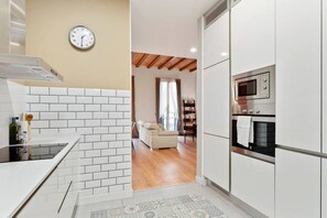 Una cucina moderna con mobili bianchi, un forno a microonde e una sveglia al muro.