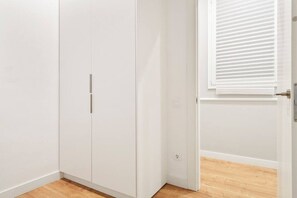 A room with white walls, a wooden floor, and a white wardrobe with two doors. - The Collection - Arc de Triomf Modern 2BD 2BTH (Barcelona)