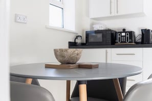 Una cocina moderna con armarios blancos, encimera negra y un microondas.