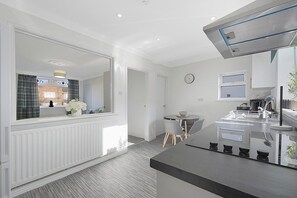 A modern kitchen with a central island, a dining area with a round table, and a large window with curtains. - Stylish home, Near Durham Heritage Coast, Sleeps 5 (Scotlandd)