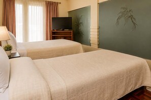 Ein Hotelzimmer mit zwei Betten, einem Fernseher auf einem Schrank und einer Pflanze.