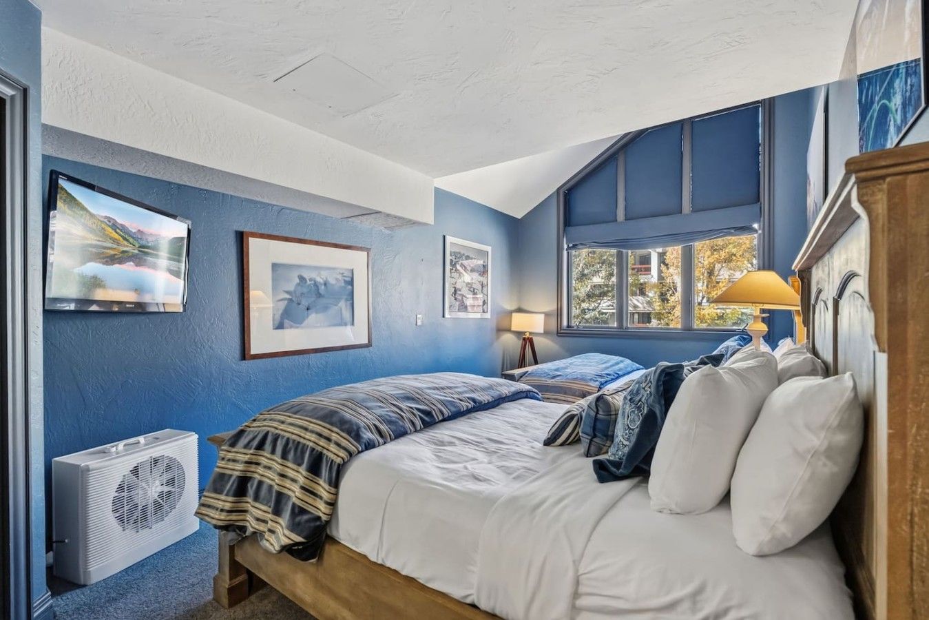 Une chambre à coucher avec un lit, une fenêtre et un climatiseur fixé au mur.
