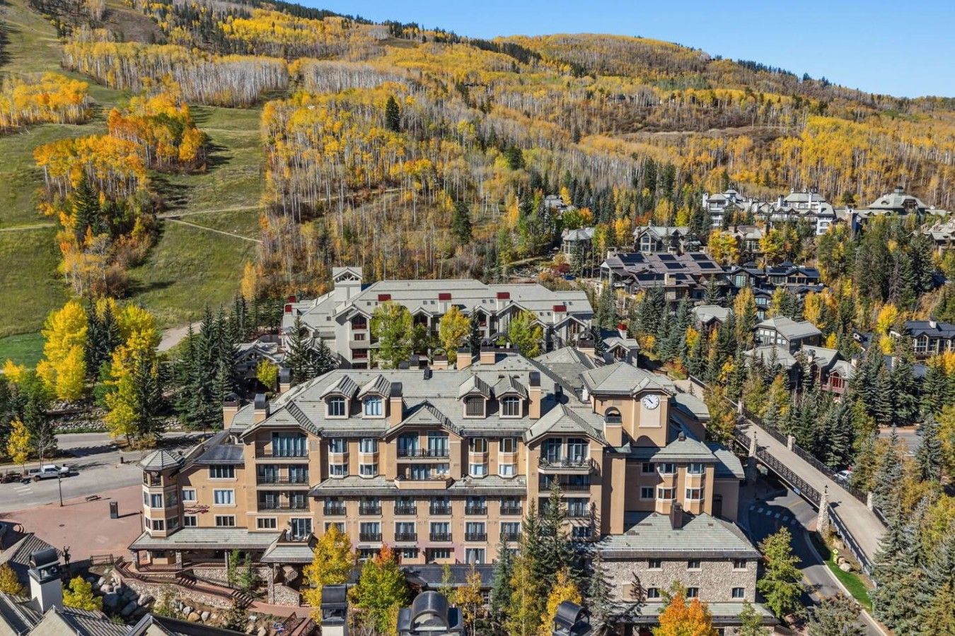 A resort with multiple buildings, a parking area, and a mountainous backdrop with autumn foliage.
