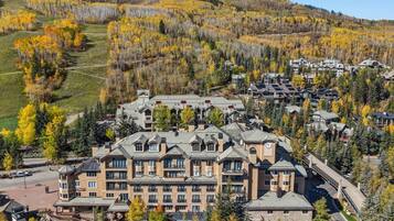 A resort with multiple buildings, a parking area, and a mountainous backdrop with autumn foliage.