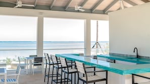 A modern kitchen with a bar area, large windows, and a view of the ocean. - 5th Floor Condo at ONE Cable Beach (Nassau)