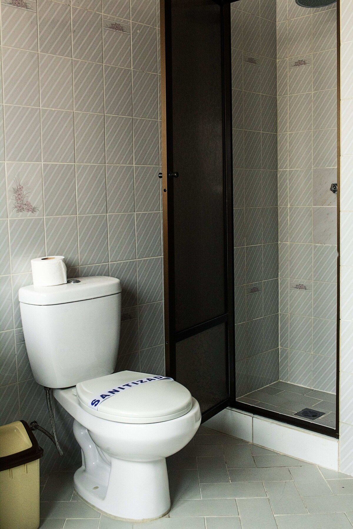 Un baño con inodoro, cabina de ducha y paredes con azulejos.