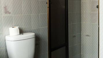 Un baño con inodoro, cabina de ducha y paredes con azulejos.