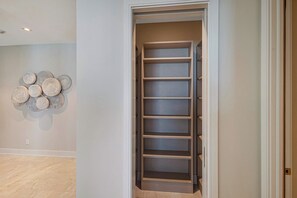 A walk-in closet with multiple shelves and a wall-mounted decorative piece. - Oceanfront Aqualina Penthouse with Infinity Pool (Nassau)