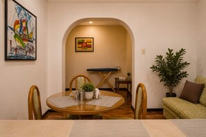 A dining area with a round table, chairs, a small side table, and a potted plant. - Calacoto Apartment, 2BR Kitchen I Sleeps 5 (La Paz)