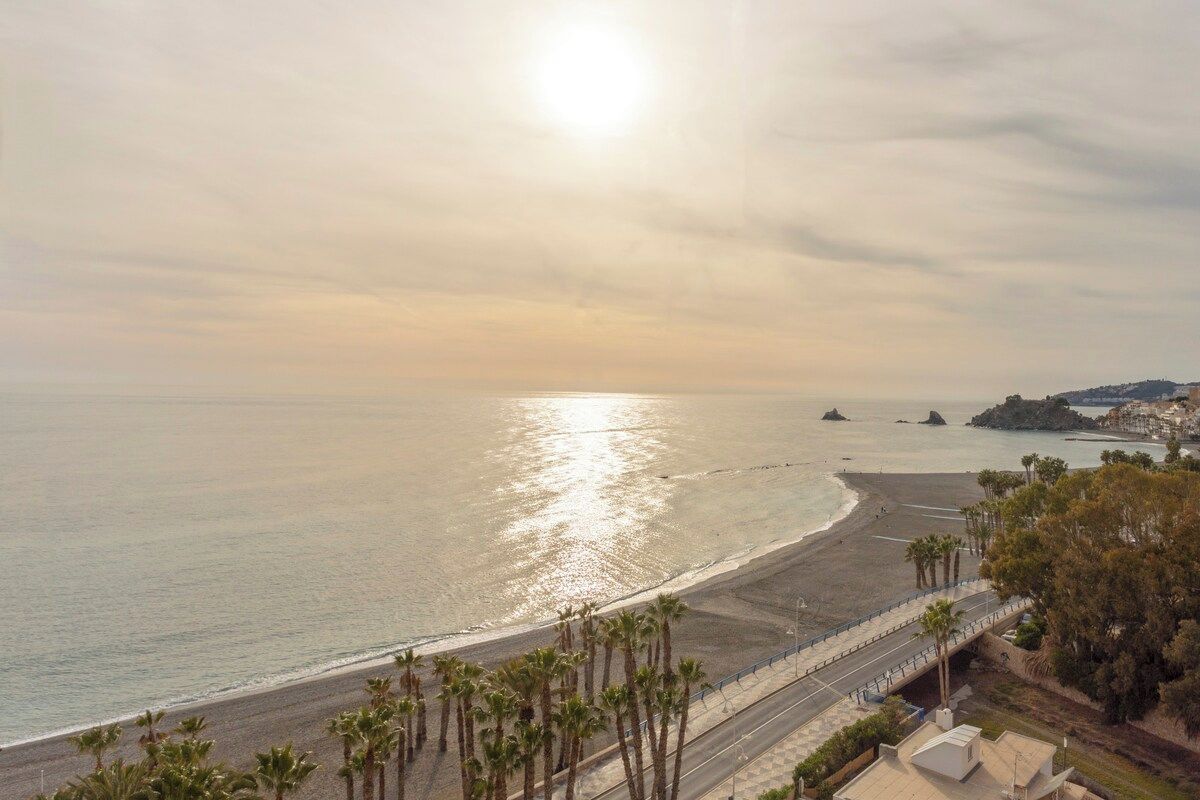 Une route côtière bordée de palmiers, une plage et un ciel dégagé.