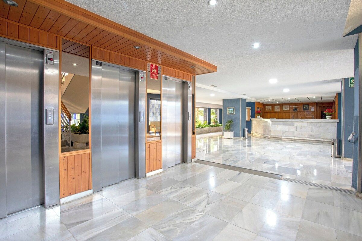 A hotel lobby with a marble floor, wooden paneling, and a reception desk.