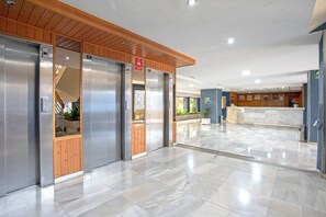 A hotel lobby with a marble floor, wooden paneling, and a reception desk. - Seafront Apartment with Parking (Almuñécar)