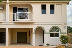 Um edifício de dois andares com varanda, várias janelas e entrada de garagem.