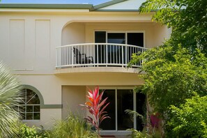 A two-story house with a balcony, large windows, and lush greenery. - 2 Bedroom Apartment near The Strand with Parking in Townsville (North Ward)