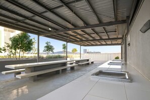 Ein Außenbereich mit einer Terrassenfläche, Betonbänken und einem Billardtisch.