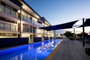 Ein modernes Hotel mit Schwimmbad, mehreren Balkonen und einem überdachten Gang.
