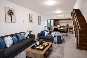 A modern living room with a sofa, coffee table, and artwork on the walls. - Townsville CBD Stadium 2BR, 2BA w Pool, Spa & Parking (Townsville City)