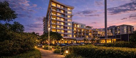 Un hôtel à plusieurs étages, doté d’un design moderne, avec des balcons à chaque étage, un chemin central et une structure imposante sur le côté droit.