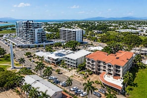 A modern urban area with high-rise buildings, a prominent white tower, and a mix of commercial and residential structures. - 1BR Apartment Waterfront views, Walk to Ferry & City (South Townsville)