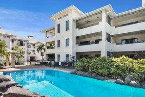 A multi-story hotel with a swimming pool, balconies, and a landscaped garden. - Townsville Waterfront Apartment with 2 BR Pool & Parking (Townsville City)