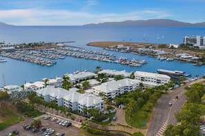 A marina with numerous boats docked, surrounded by residential buildings and a clear view of the sea. - Townsville Waterfront Apartment with 2 BR Pool & Parking (Townsville City)