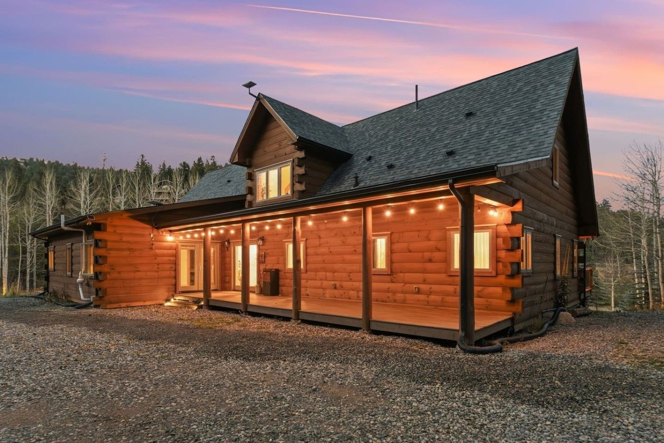 A log cabin with a porch, large windows, and a chimney.