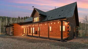 A log cabin with a porch, large windows, and a chimney.