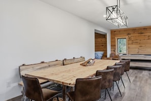 A modern dining area with a large wooden table, leather chairs, and a geometric pendant light. - Evergreen Escape | Sauna, Theater Room | 6.5 Acres (Evergreen)